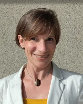 Frau, offen, freundlich schauend, in hellem wollweiss farbenen Blazer mit gelben Top